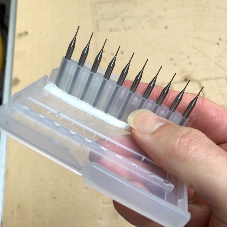 A box containing a set of ten router bits with tiny tips.