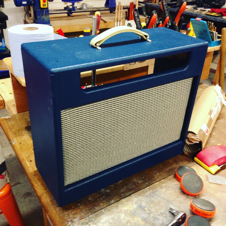The cabinet still on the workbench, but now in the face there is silver grill cloth where the speaker should be.