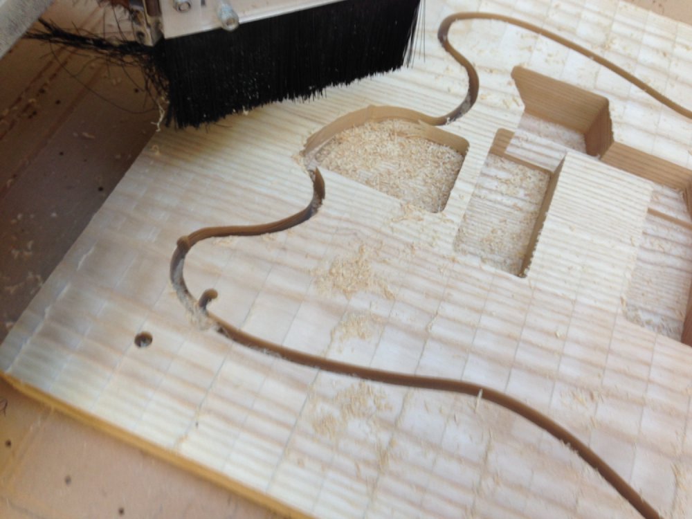 The block of wood looks more like a guitar, with the outline of the body cut, but you can see where the machine took a wrong turn and cut into the body core when it shouldn't have.