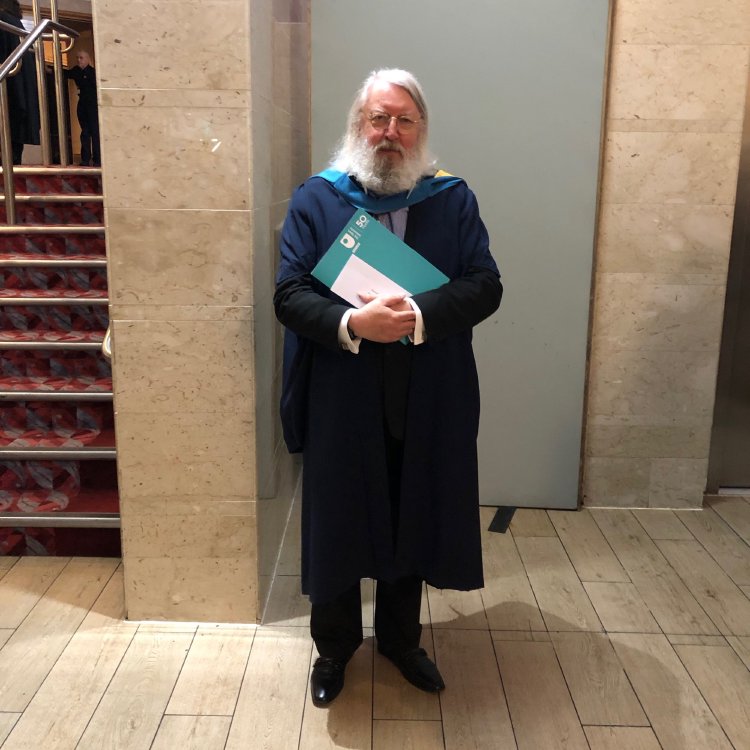 A photo of my father in a suit, with an academic gown on, clutching his graduation certificate.