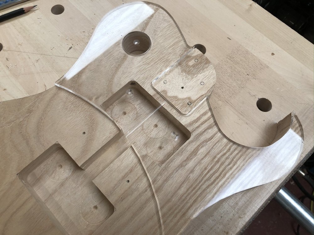 The guitar body has a laser-cut clear-acrylic template over it. If you look closely you can see the screw mount holes in the template are over the gaps in the body where the pickups go.
