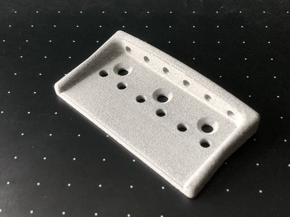 A more traditional looking guitar bridge-plate printed in a course looking plastic material.