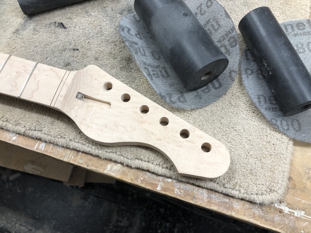 The neck is surrounded by sanding disks and the rubber cylinders from a spindle sander around which some of the disks are wrapped.