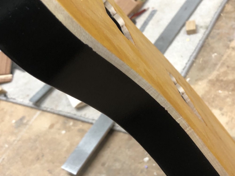 A close-up photo of the side of the guitar, showing the yellow stained top, then the top 5mm of the side next to the yellow top is natural wood finish, then then the rest of the side is painted black. You can just see that the line between black and natural is mostly a crisp line, but in a few places paint has seeped over the edge ruining the effect a little.