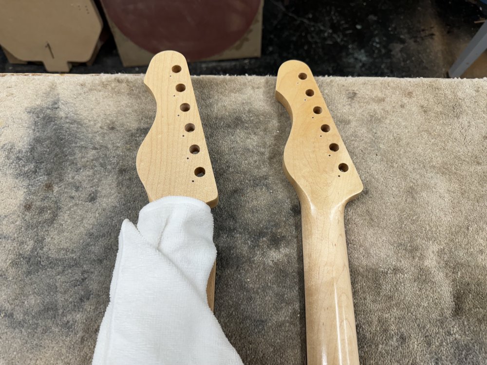 A close-up photo of the two guitar necks showing their headstocks now have the 6 large holes (10mm) for the tuners to fit through and next to each big hole is now an additional small hole (2mm) for the locating screw on the tuners.