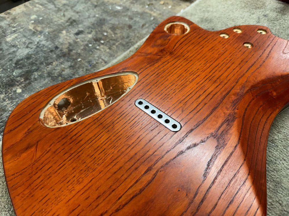 A photo of the guitar body again from the back, showing that the string-ferrule block is now installed snuggling until the back of the guitar, sitting flush with the surrounding wood.
