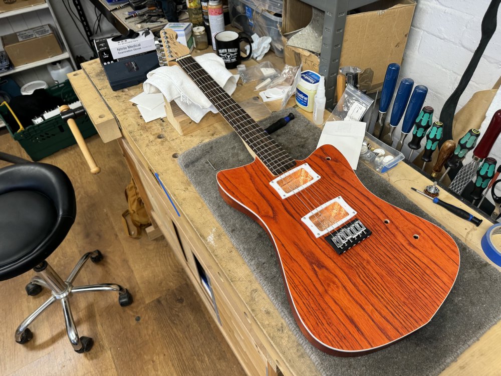 A mostly assembled guitar sits on the workbench! It is missing all the electronics, but otherwise looks like a guitar. Importantly it has strings on it!