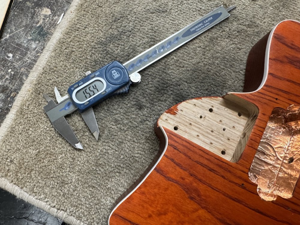 A close-up photo of the neck pocket of a guitar body, and next to that is a set of callipers showing 15.54 mm.