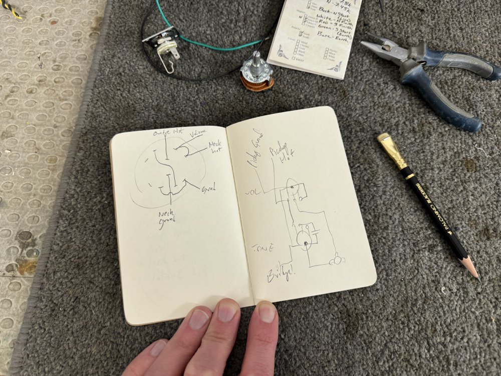 A photo of my little notebook, showing hand drawn in pencil on the left page the wiring for the connectors on the rotary switch and on the right page for the volume and tone controls.