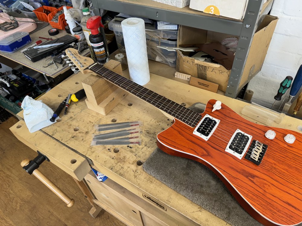 A photo of the strung up guitar on the workbench, next to which sit a bunch of small files used to cut the slots in the nut.