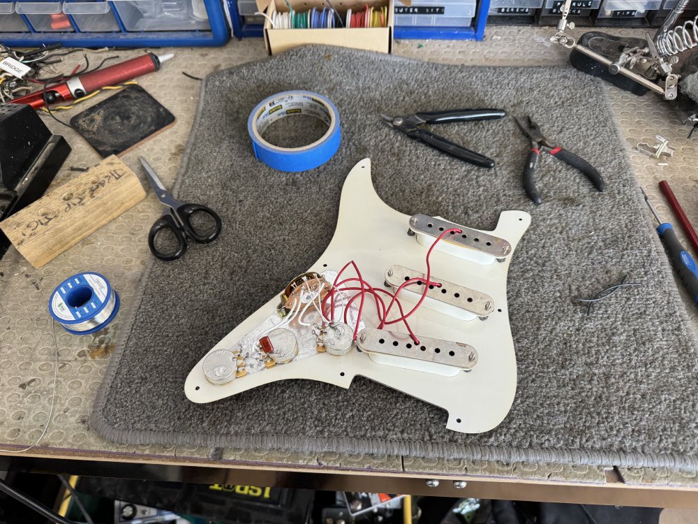 Another view of the backside of the pickguard, and now there are a bunch of red and white wires running between all the parts.
